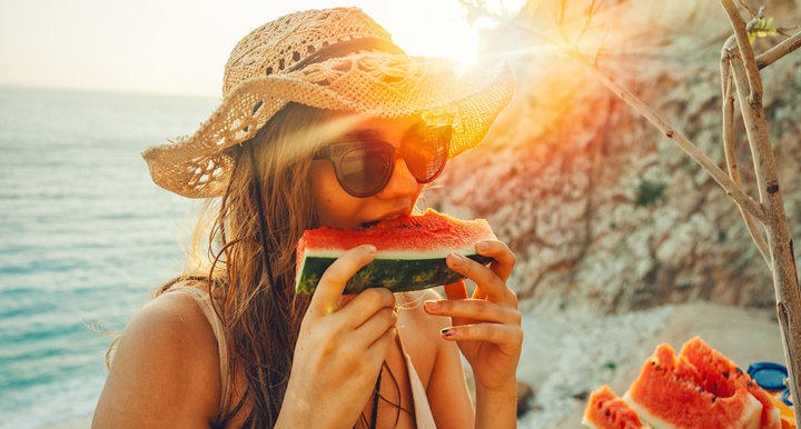 young woman having fun and eating juicy fresh watermelon outdoor at sunset time with snuffler in summer time